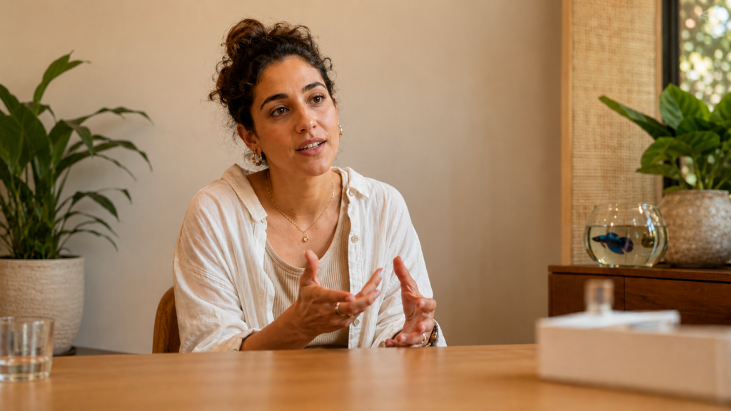 מטופלת יושבת בפגישת ייעוץ בקליניקה הומאופתית מוארת ומדברת בפתיחות - הומאופתיה לאנדומטריוזיס